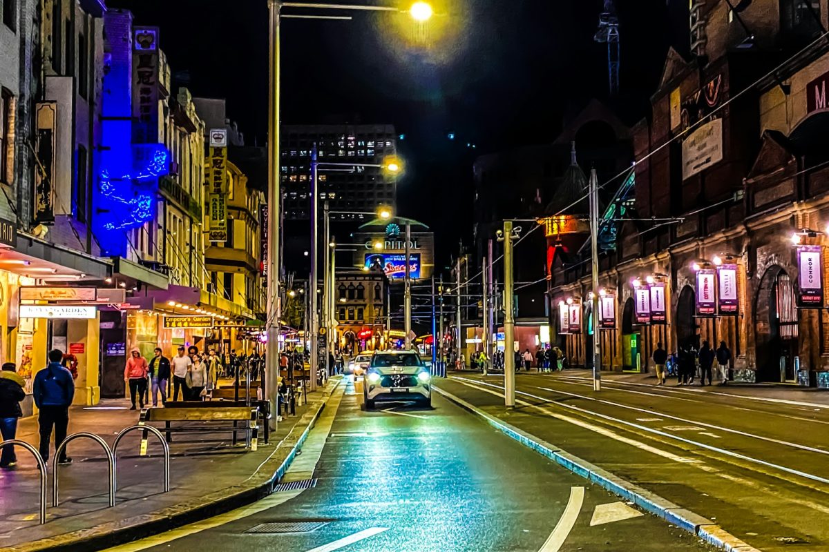 A city street at night with people walking on the sidewalk